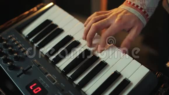 穿着kosovorotka衬衫的人手快速敲击MIDI控制器键盘的键视频的预览图
