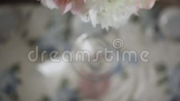 年轻女子在餐桌上装饰鲜花在高玻璃花瓶中装饰鲜花节日餐桌装饰婚礼视频的预览图