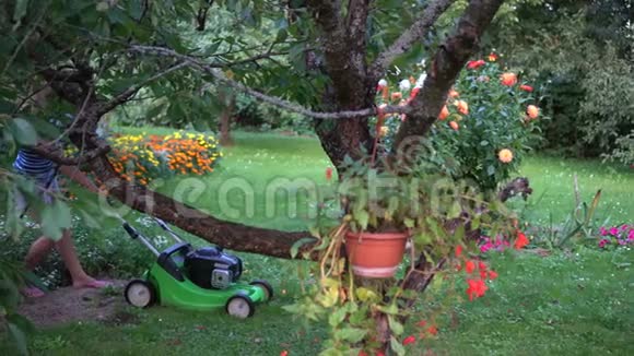 园丁女启动割草机引擎在花园里割草视频的预览图
