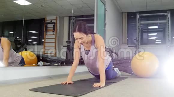 培训一位年轻女子在健身房做俯卧撑视频的预览图