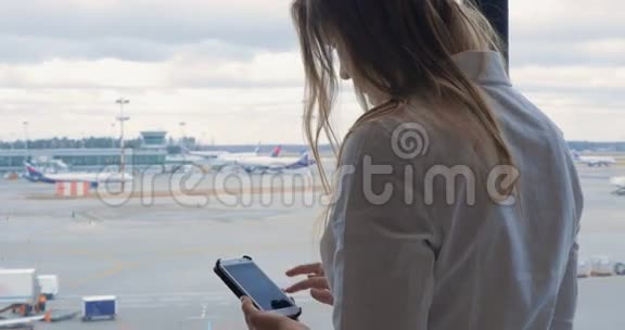 女人在手机上发短信看着机场视频的预览图