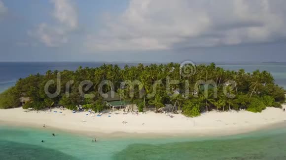 相机围绕着一个圆形的热带环礁岛度假酒店飞来飞去那里有白沙棕榈树和绿松石视频的预览图