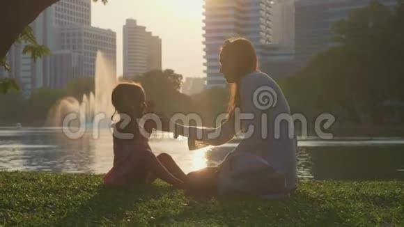 一家人在公园里玩湖和背景上的摩天大楼视频的预览图