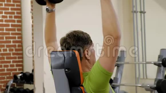 一个人坐在健身室里用哑铃做长凳按压视频的预览图