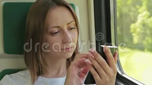 坐在火车上的有手机的年轻女子视频的预览图