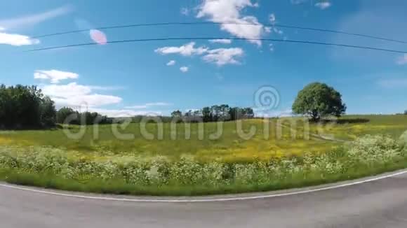 在有绿色牧场和森林背景的道路上驾驶汽车视频的预览图