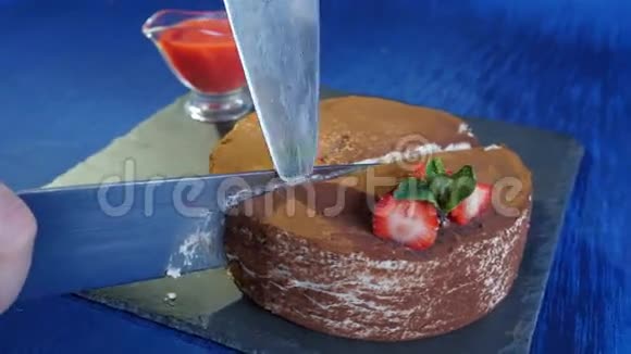 女性切巧克力蛋糕草莓在木桌上深蓝色背景玻璃巧克力蛋糕切片视频的预览图