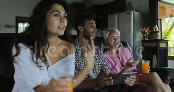 人们用平板电脑观看直播电视在客厅喝果汁年轻人和妇女团体在晨谈视频的预览图