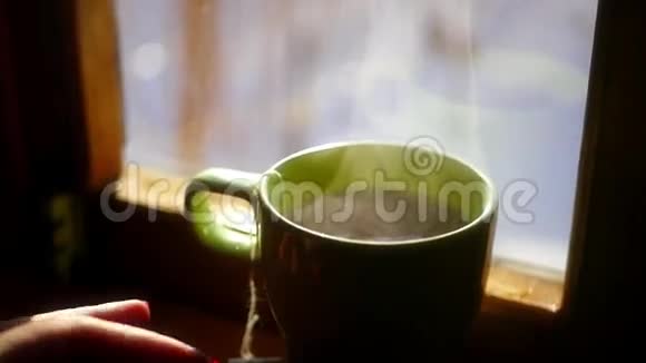 拿一杯带茶袋的热水来泡一杯红的来来回回用明亮的太阳对着窗户泡一杯美味的茶视频的预览图