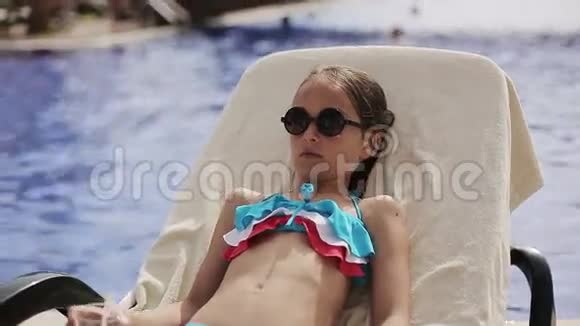 泳池里的小女孩在阳光休息室里放一杯鸡尾酒视频的预览图