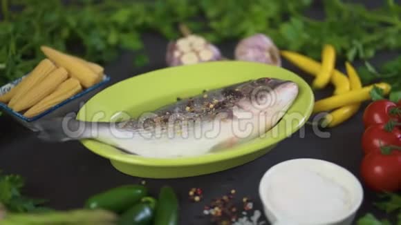 新鲜的生的多拉达鱼放在绿色的盘子里黑桌上放着一套蔬菜视频的预览图