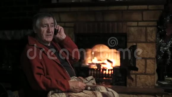坐在壁炉前的老人用手机说话视频的预览图
