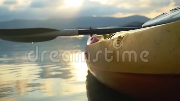 海滩上的独木舟从海边向前看在美丽的夏季日落时在平静的水面上划艇有镜头耀斑效果没有视频的预览图