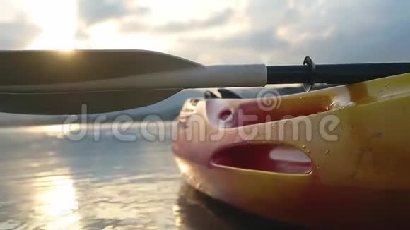 海滩上的独木舟从海边向前看在美丽的夏季日落时在平静的水面上划艇有镜头耀斑效果没有视频的预览图