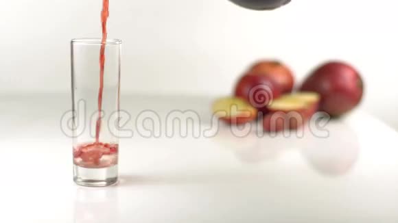 在苹果模糊的背景下空杯子里满是红色的果汁视频的预览图