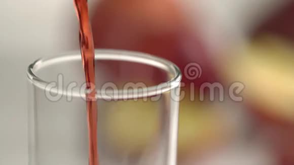在水果模糊的背景下红色果汁涌入空玻璃的特写镜头视频的预览图