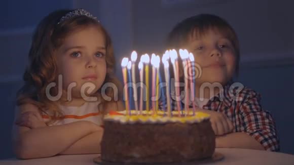 一个小男孩和一个女孩在一个庆祝蛋糕上看许愿然后在蛋糕上吹蜡烛视频的预览图