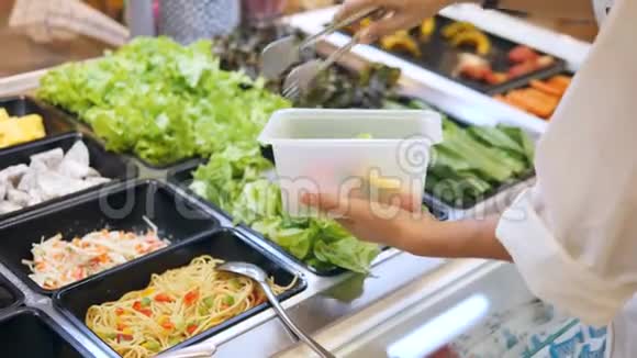 年轻女性在食品店沙拉酒吧购买有机蔬菜素食者远离食物健康饮食视频的预览图