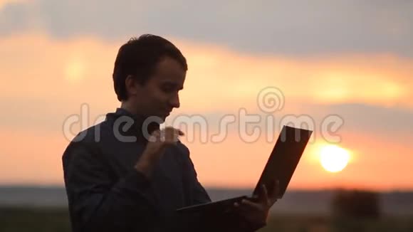 一个男人在笔记本电脑上打视频电话背景上美丽的日落视频的预览图