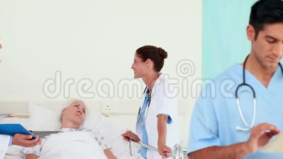 医生在看平板电脑而他的同事在和病人说话视频的预览图