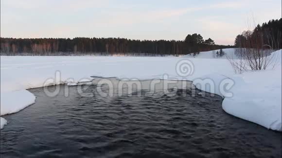 从湖中流出的水在俄罗斯西伯利亚的日落雪中流淌视频的预览图
