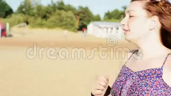 快乐的年轻女孩在海滩上奔跑微笑在镜头里夏日阳光明媚假期视频的预览图