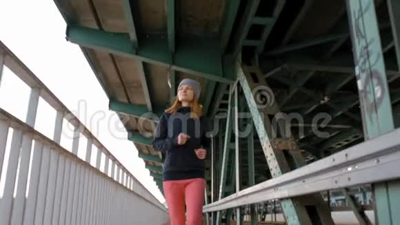 年轻女士在城市工业桥上奔跑的慢动作视频的预览图