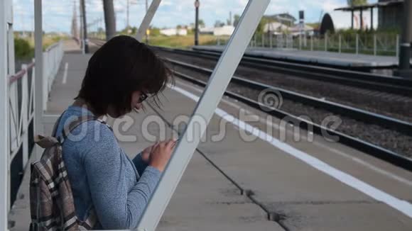 有手机的女旅客在站台上等候火车视频的预览图