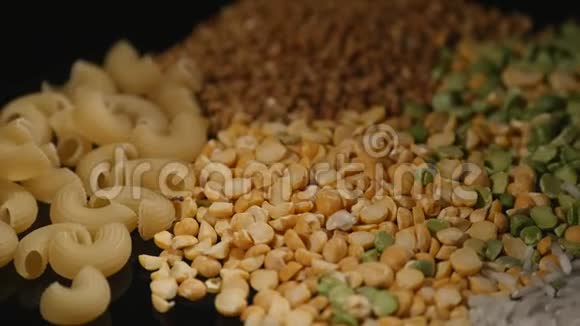谷物豌豆扁豆大米荞麦面食混合在黑色背景上旋转视频的预览图