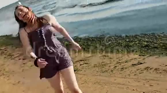 快乐的年轻女孩在海滩上奔跑对着镜头微笑海洋夏日阳光明媚视频的预览图