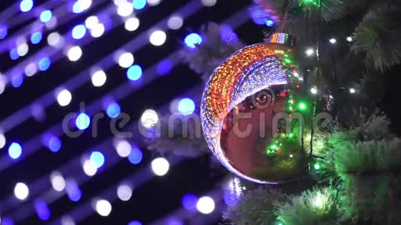 大圣诞球挂在圣诞树上背景模糊的灯光花环上视频的预览图