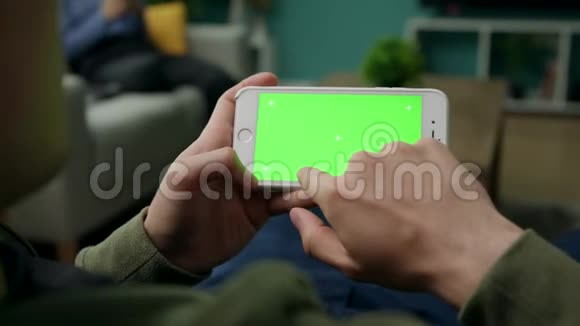 男人在家坐在沙发上用智能手机加绿色锁屏视频的预览图