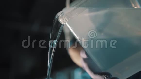 男性用橡胶手套向方形塑料容器倒水视频的预览图
