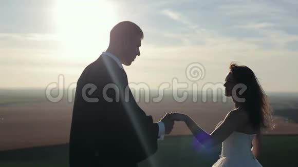 新娘和新郎在夕阳下的山岩上牵手视频的预览图