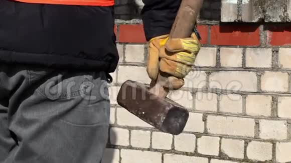 砖墙附近有大锤的工人视频的预览图