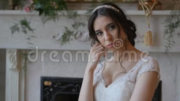 美丽活泼的黑发新娘穿着白色连衣裙摆在壁炉背景上视频的预览图