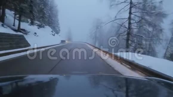 黑车正在郊区的道路上行驶在积雪覆盖的树木和山丘中视频的预览图