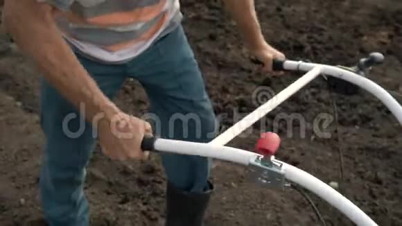 一个人是郊区的农民一个菜园用一个耕种者一个手动马达犁投掷粘土和视频的预览图