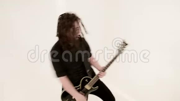 时尚的独奏吉他手头上戴着可怕的石头白色背景上穿着黑色衣服富有表现力地演奏着视频的预览图