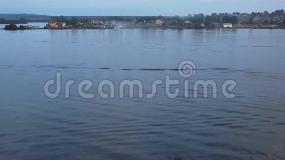 在粉红色的夕阳下从城市池塘水面上的一艘船上留下的痕迹视频的预览图