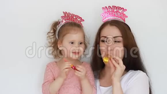 生日快乐一个女人和她的孩子微笑玩得开心笑和庆祝母亲和女儿吹着派对的号角视频的预览图