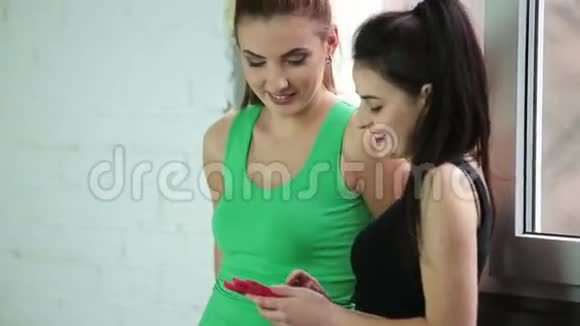 年轻的健身女孩在健身房使用智能手机视频的预览图