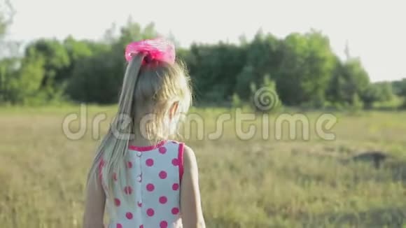 穿着红色图案的白色短裙跑过田野的小女孩视频的预览图