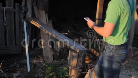 日落时拿着手机的年轻人一个男人坐在锯木厂视频的预览图