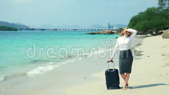 商人和女商人带着一个手提箱沿着岛上白色的沙滩散步视频的预览图