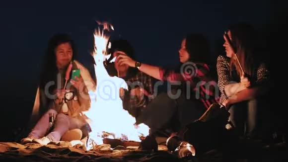 几个女孩晚上坐在炉火旁煎香肠讨论并领导谈话参加竞选视频的预览图