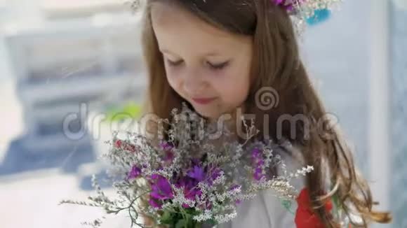 蓝眼睛和鲜花的小女孩在镜头前微笑4K视频的预览图