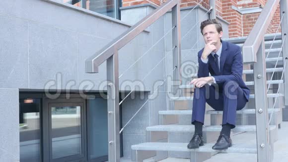 年轻的商人坐在办公室外的楼梯上视频的预览图
