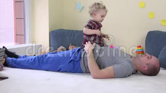 可爱的女婴坐在爸爸的肚子上拥抱慈爱的父亲视频的预览图