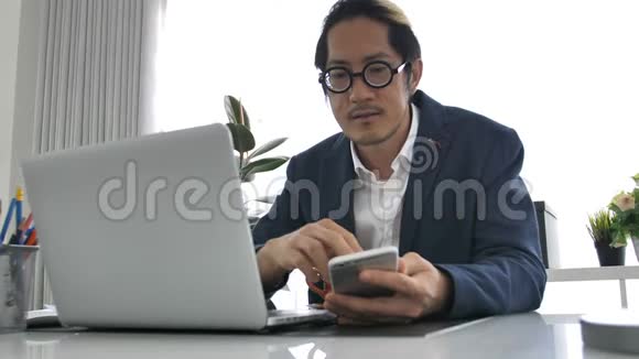 商务人员在办公室使用笔记本电脑和手机视频的预览图
